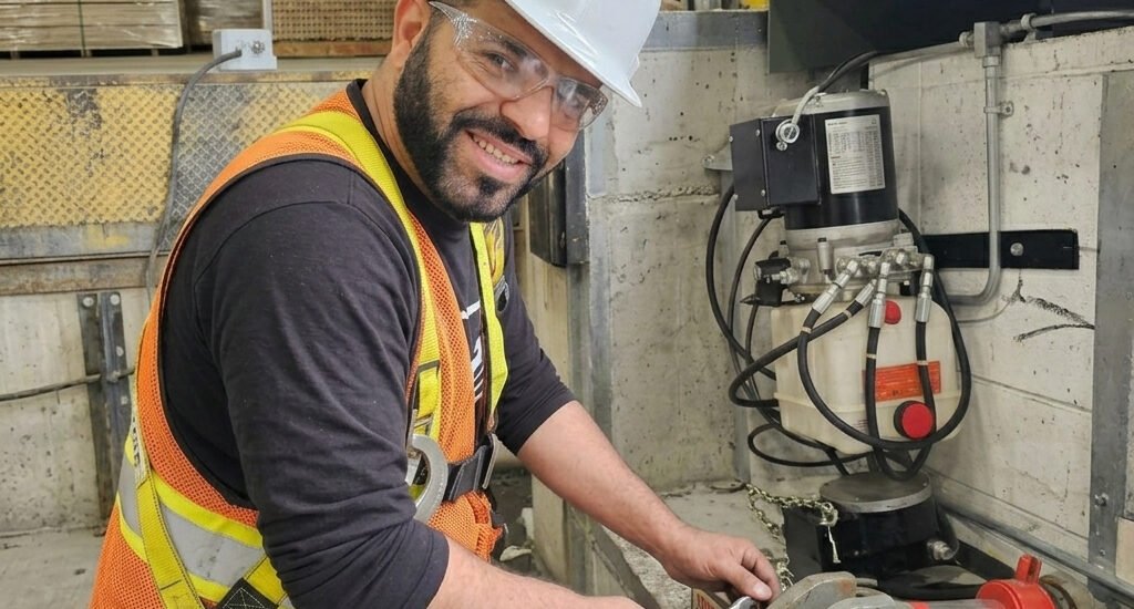 Technicien ajustant le système hydraulique d'un nivelateur de quai de chargement avec une clé anglaise