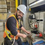 Technicien ajustant le système hydraulique d'un nivelateur de quai de chargement avec une clé anglaise