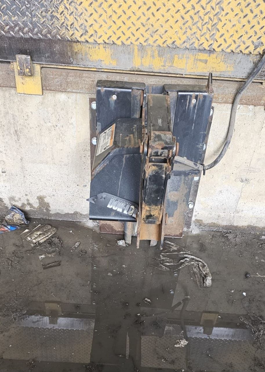 Système de retenue de camion automatique installé au pied d'un quai de chargement industriel avec nivellement